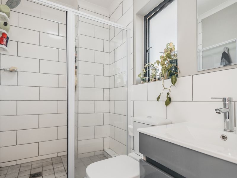 A modern bathroom featuring a glass-enclosed shower, subway-tiled walls, a sleek vanity with a basin, and a wall-mounted mirror.