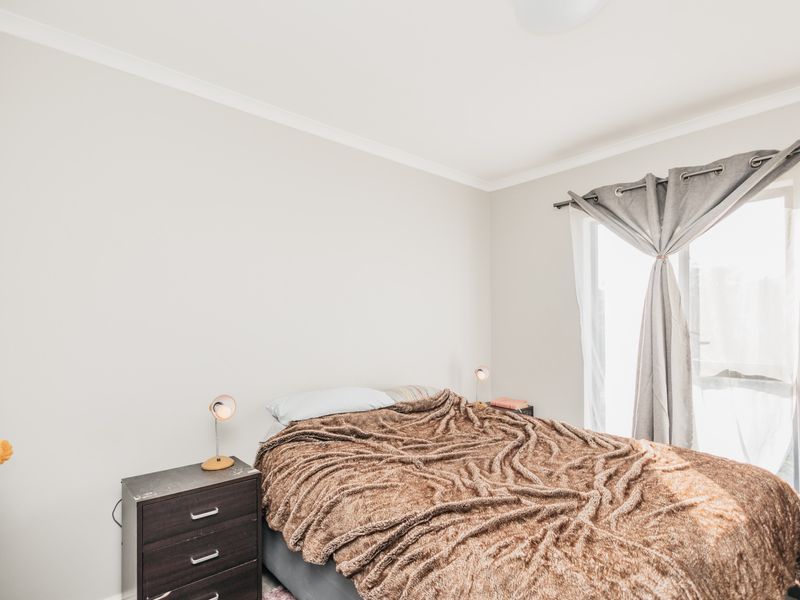 A well-lit bedroom featuring neutral walls, a built-in wardrobe, and a window with installed curtain hardware.
