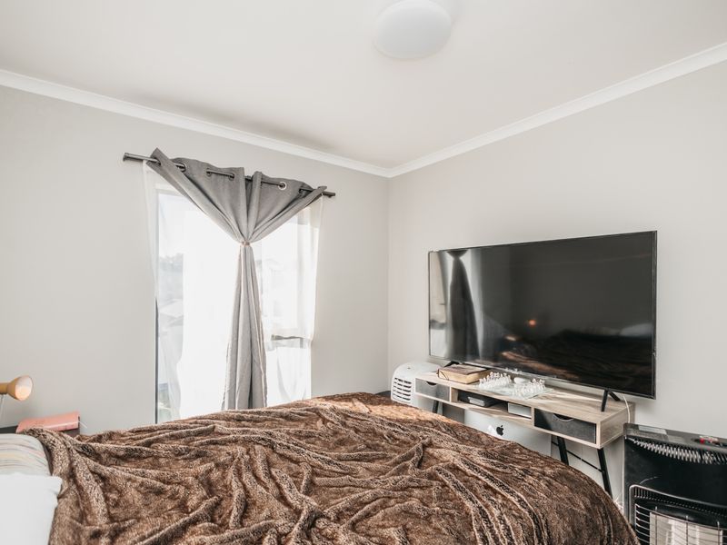 A well-maintained bedroom featuring neutral wall tones, coving, and a window with a fitted curtain rod.