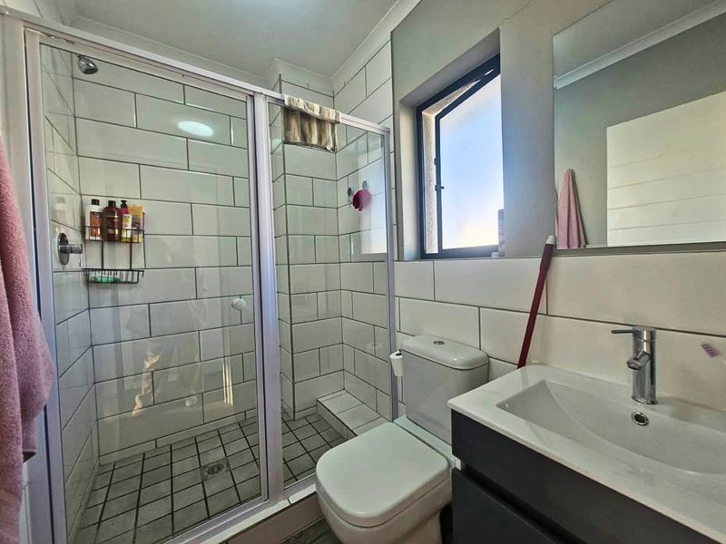 Compact bathroom featuring a glass-enclosed shower, modern vanity basin, and subway-tiled walls, providing a functional and clean space.