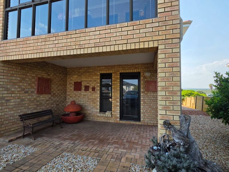 A covered ground-level patio featuring face-brick walls, paved flooring, and direct access to the home through a modern glass-panelled door.