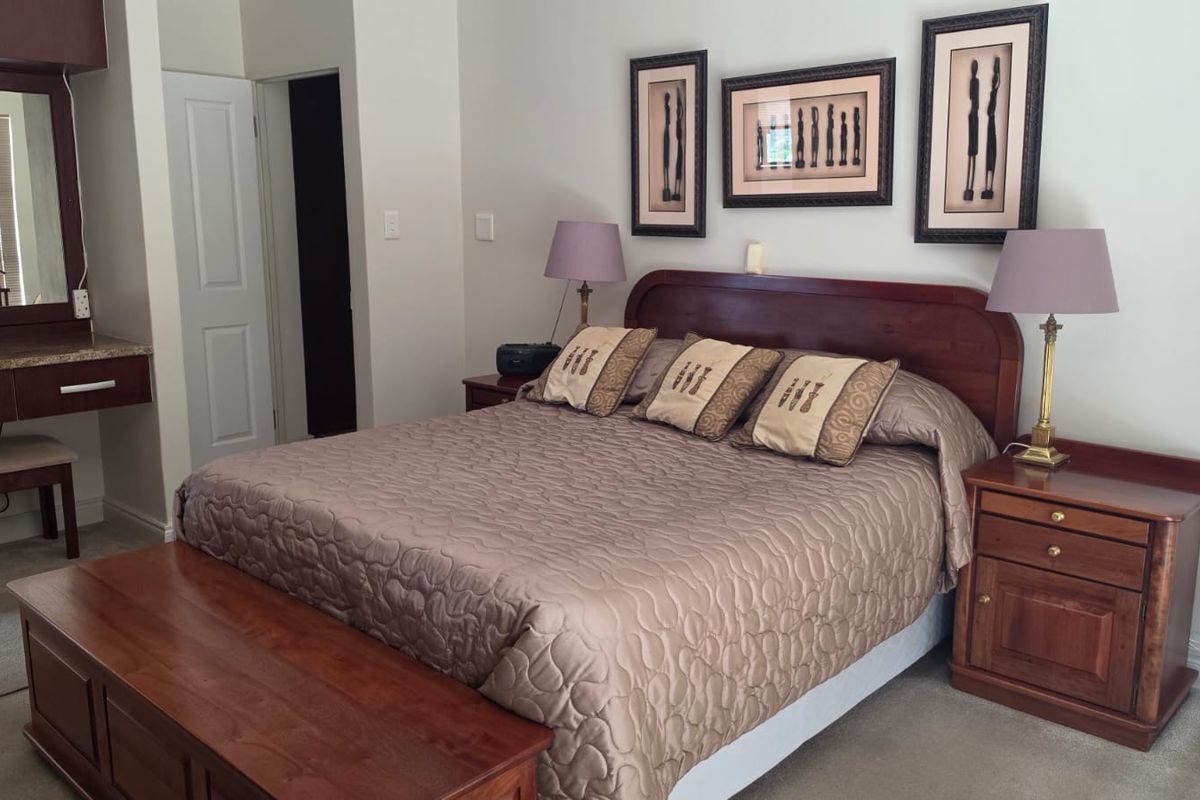 A well-maintained bedroom featuring neutral walls, carpeted flooring, and a built-in vanity unit, offering a functional and comfortable living space.