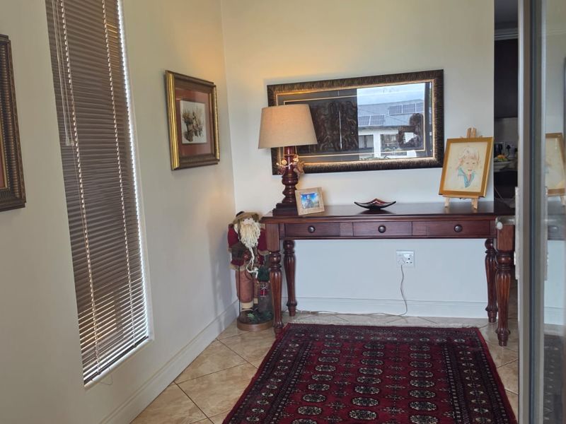 A welcoming entry area featuring neutral walls, tiled flooring, and natural light provided by a window with fitted venetian blinds.