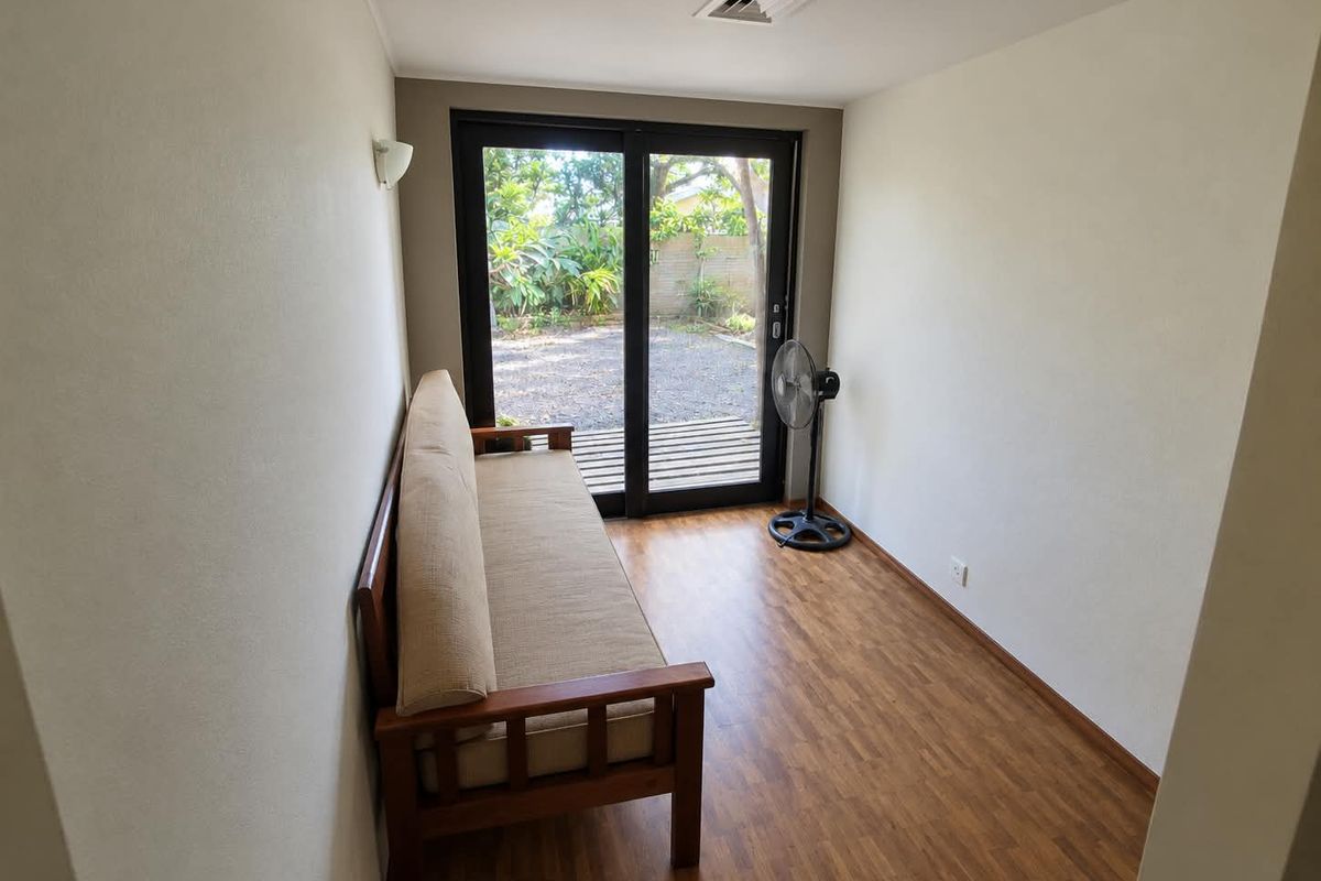 A bright living space featuring laminate flooring and a large sliding glass door providing direct access to the rear garden area.