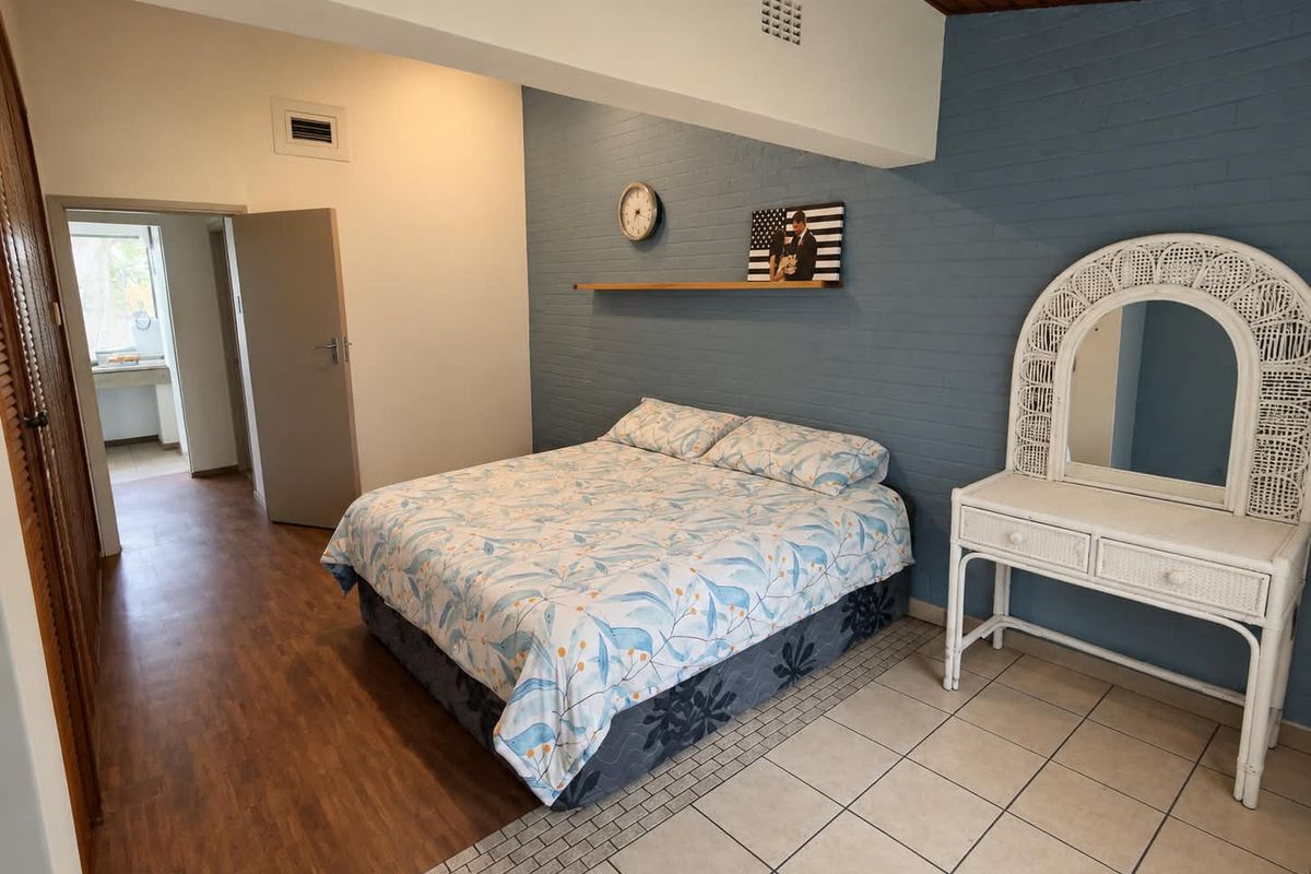 Spacious bedroom featuring a mix of laminate and tiled flooring, an exposed blue brick feature wall, and built-in cupboard storage.