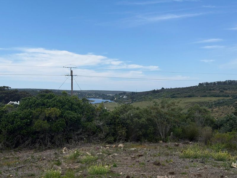 A scenic landscape view overlooking a valley with a river, featuring natural vegetation and overhead utility infrastructure.