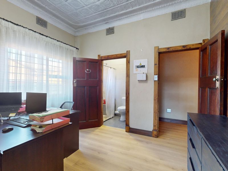 A functional home office featuring classic pressed metal ceilings, laminate flooring, and direct access to an adjoining bathroom.
