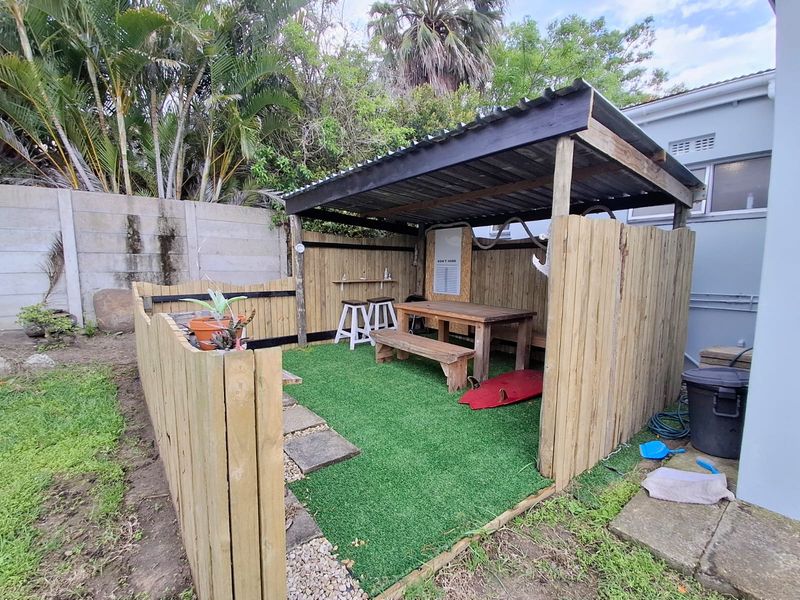 A covered outdoor patio area featuring a timber pergola structure, artificial turf flooring, and perimeter timber fencing, suitable for casual outdoor entertaining.