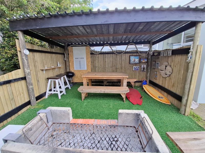 Covered outdoor patio area featuring a built-in masonry braai, artificial turf flooring, and timber privacy fencing, ideal for casual outdoor entertaining.