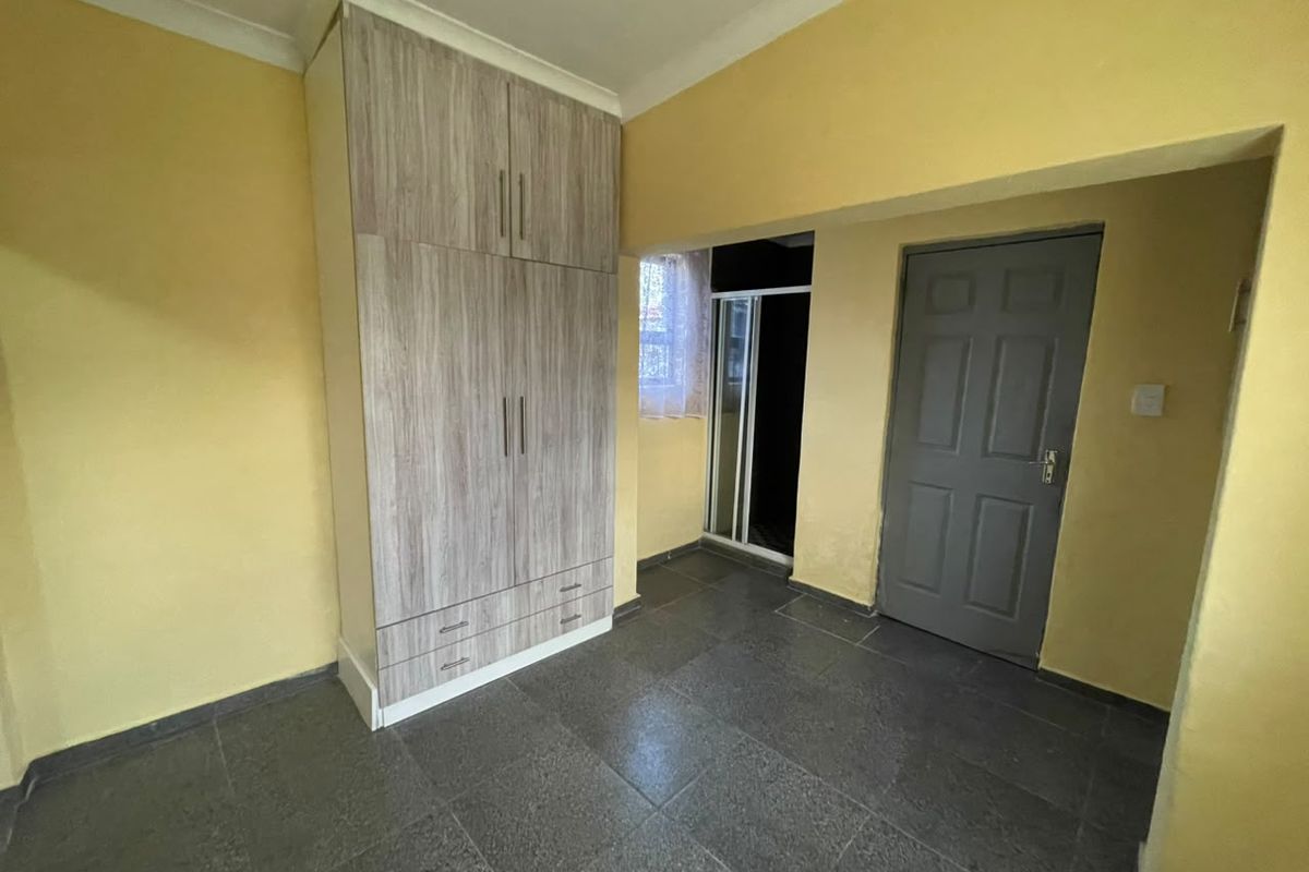 A bedroom featuring tiled flooring, a built-in wardrobe with wood-grain finish, and yellow painted walls.