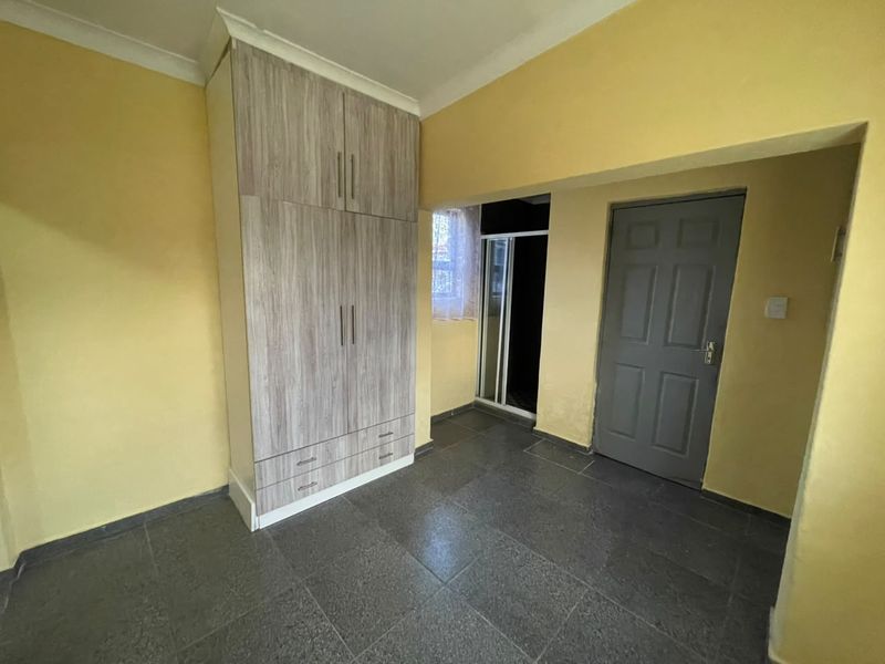 A bedroom featuring tiled flooring, a built-in wardrobe with wood-grain finish, and yellow painted walls.