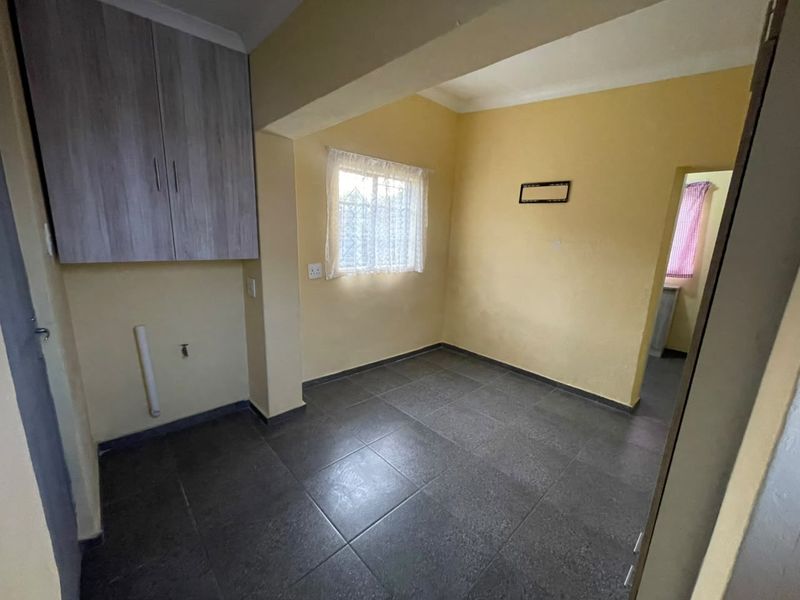 A functional laundry area featuring tiled flooring, built-in overhead cabinetry, and dedicated plumbing connections for appliances.