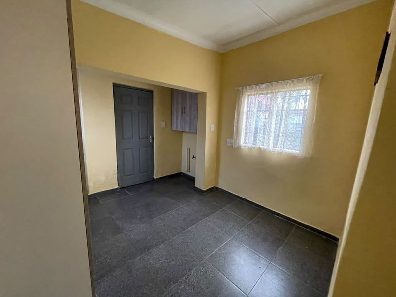 A functional laundry area featuring dark tiled flooring, a built-in wall cabinet, and dedicated plumbing connections for laundry appliances.