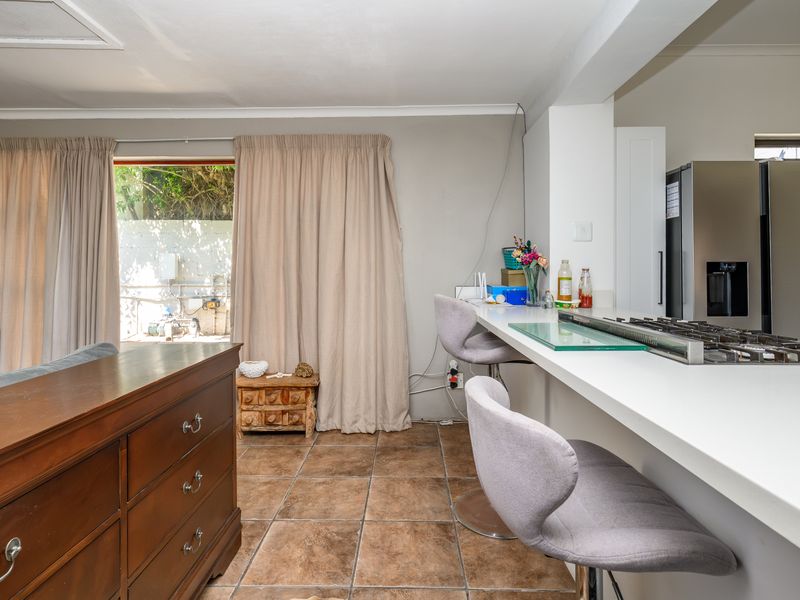 Open plan living area featuring a breakfast bar with integrated gas hob, tiled flooring, and direct access to the outdoor area via sliding doors.