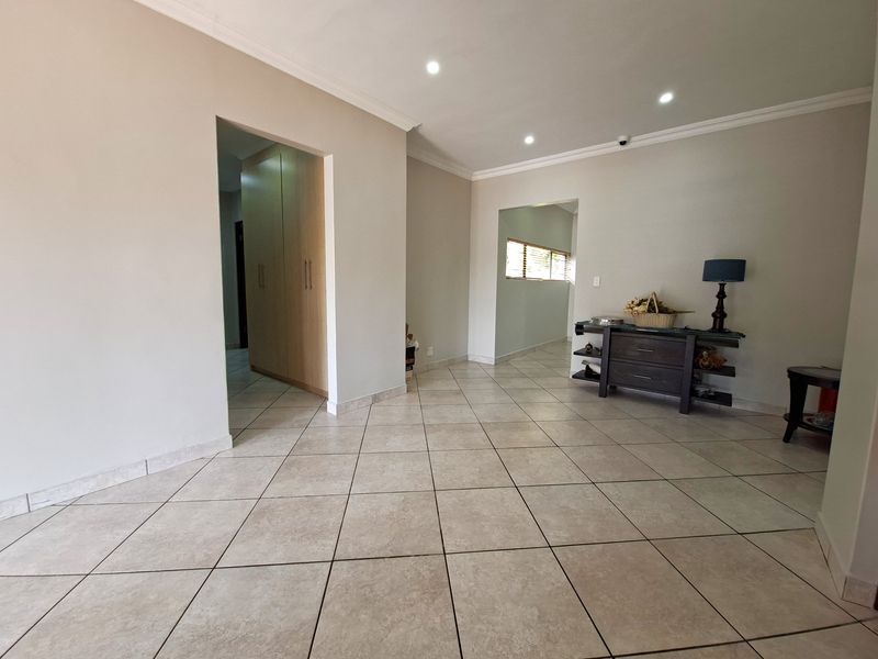 A spacious living area featuring neutral tiled flooring, recessed downlighting, and elegant cornicing, providing a clean and versatile foundation for interior design.
