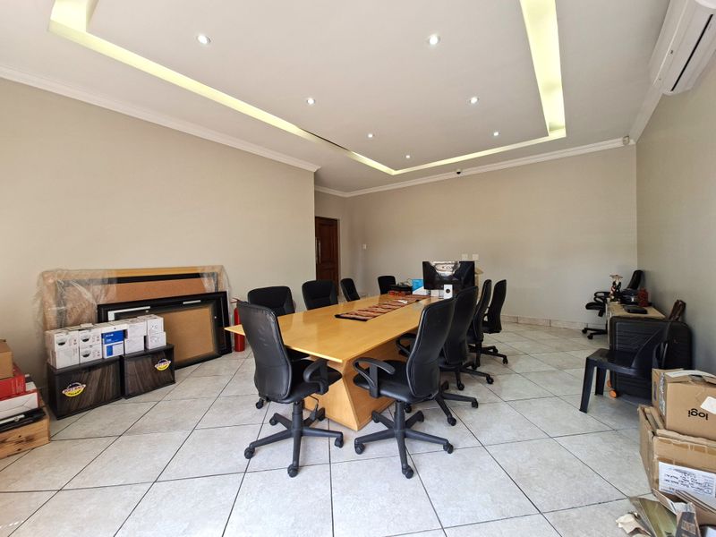 Spacious office area featuring a tray ceiling with recessed lighting, ceramic tiled flooring, and a wall-mounted air conditioning unit.