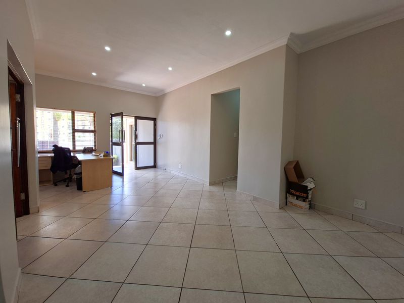 Spacious living area featuring neutral ceramic floor tiles, recessed downlighting, and coved cornicing, providing a clean and versatile space for various interior layouts.