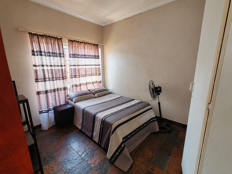 A compact bedroom featuring tiled flooring and a built-in wardrobe, offering a functional space that could benefit from cosmetic updates.