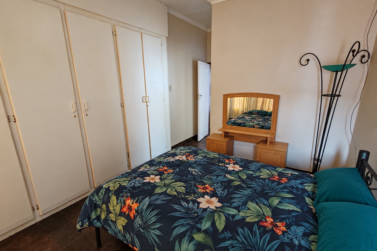 A functional bedroom featuring built-in cupboards and tiled flooring, offering a neutral base for personalization.
