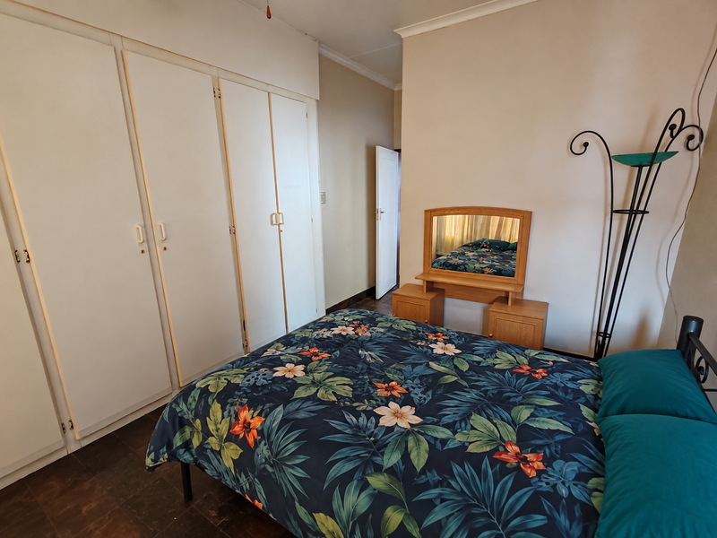 A functional bedroom featuring built-in cupboards and tiled flooring, offering a neutral base for personalization.
