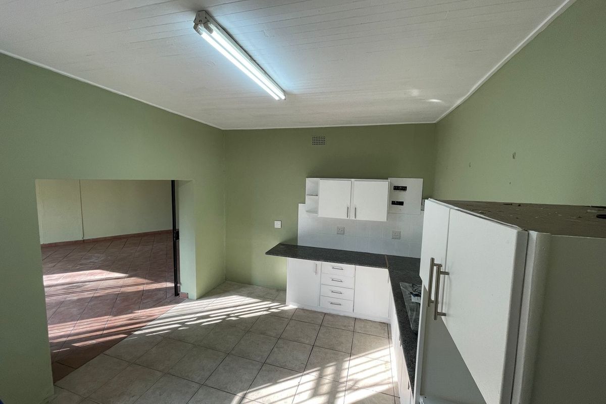 A functional kitchen space featuring white built-in cabinetry, dark laminate countertops, and tiled flooring, offering a blank canvas for potential renovation and modernization.