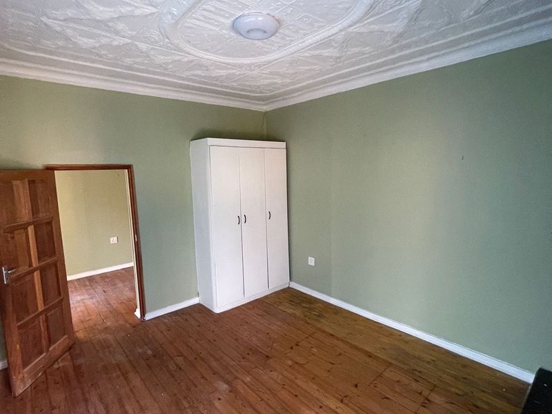 A bedroom featuring original pressed metal ceilings, polished timber flooring, and a built-in wardrobe, offering a classic character aesthetic ready for modern updates.