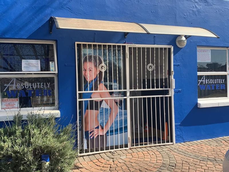 Front facade of a commercial property featuring a security gate, awning, and paved entrance area with blue painted exterior walls.