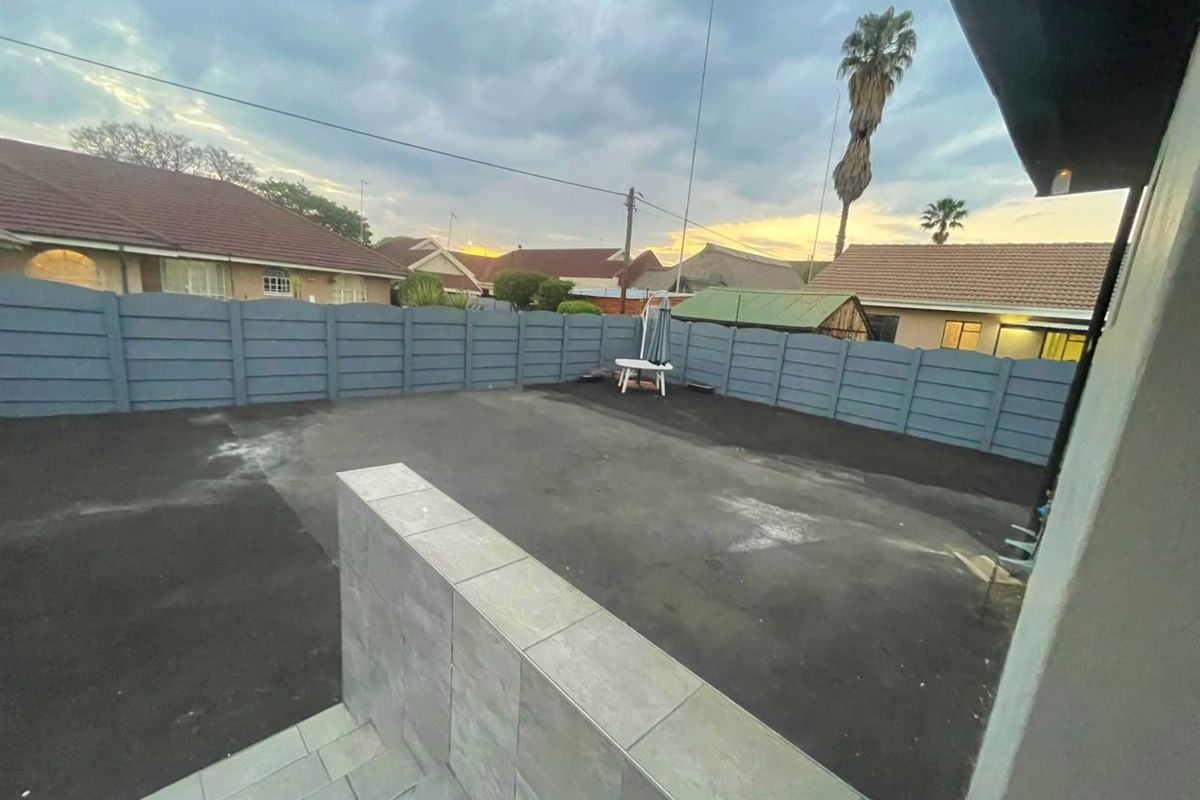 A paved rear courtyard area enclosed by a precast concrete boundary wall, featuring a low tiled feature wall.