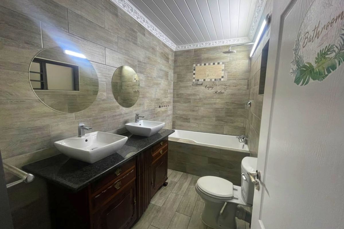 Modern bathroom featuring a double vanity with vessel sinks, granite countertop, built-in bathtub, shower, and stylish wood-look wall and floor tiling.