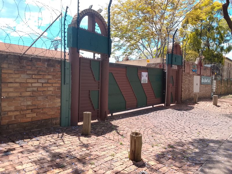 Secure front entrance featuring a sliding gate, brick boundary wall, and integrated electric fencing with razor wire protection.