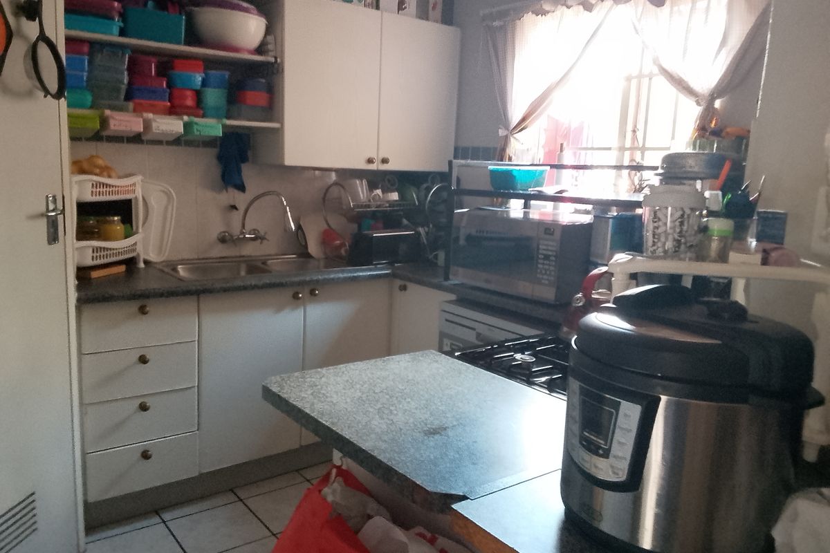 A functional kitchen featuring white built-in cabinetry, a double sink, laminate countertops, and a gas hob with tiled flooring.
