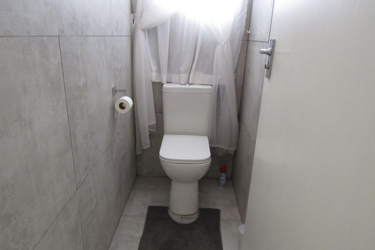 A compact bathroom featuring modern grey wall and floor tiles and a standard white toilet suite.