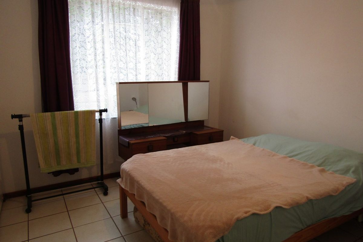 A bedroom featuring tiled flooring and a window with curtains, offering a functional space ready for modernization.
