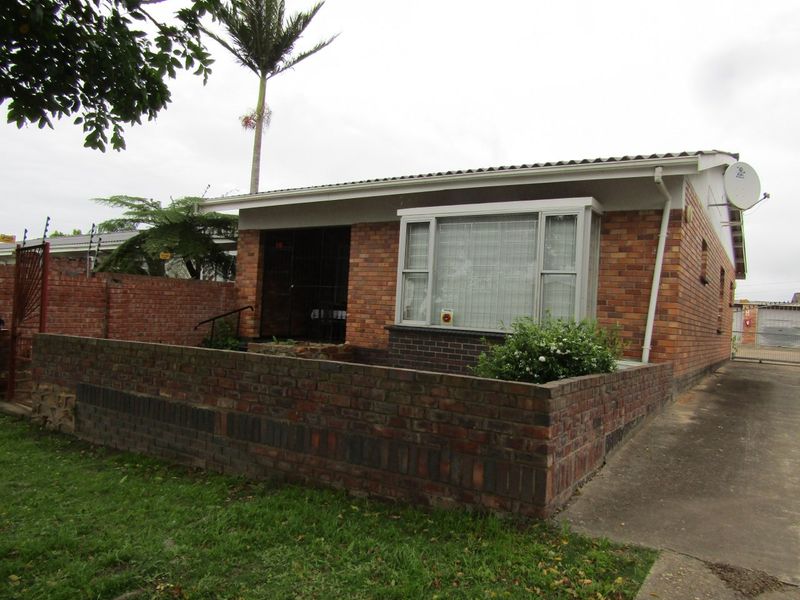Front exterior view of a single-story brick flat featuring a bay window, security gate, and a low brick boundary wall.
