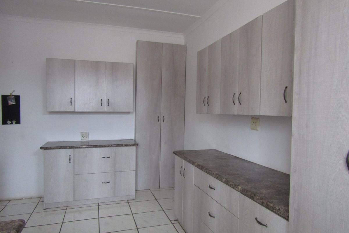 A clean, functional kitchen area featuring light wood-look cabinetry, ample storage space, and durable tiled flooring.