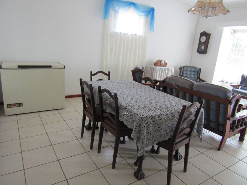 Open plan living and dining area featuring neutral ceramic floor tiles and ample natural light.