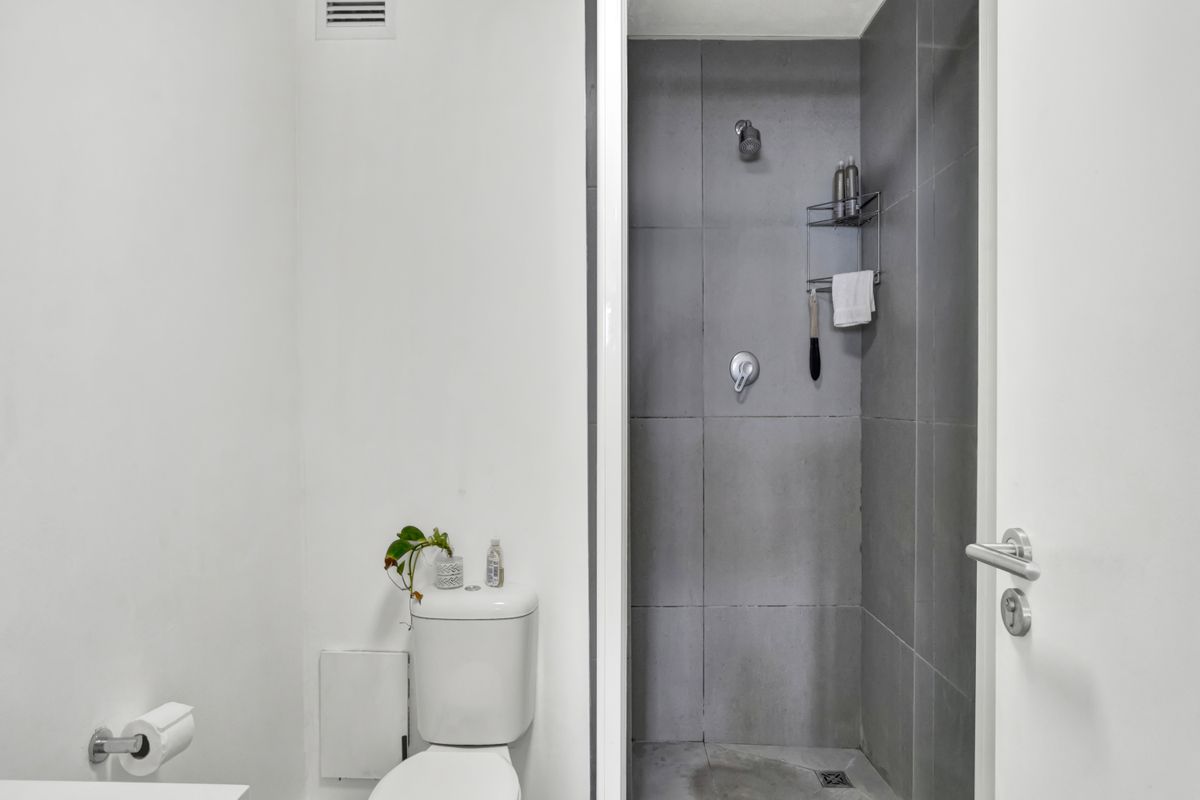 A compact bathroom featuring a modern walk-in shower with grey tiling and a standard white toilet.