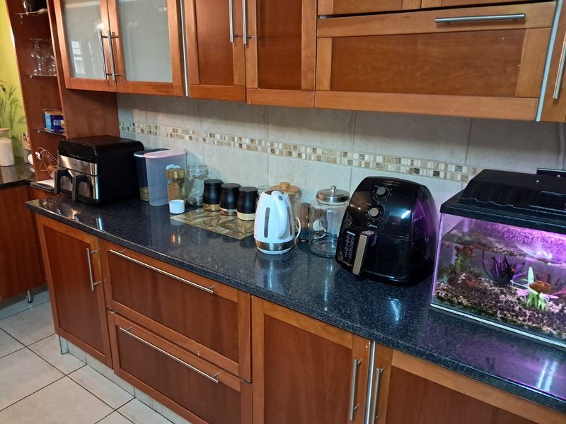 A functional kitchen featuring warm-toned wooden cabinetry, dark granite countertops, and a decorative tiled backsplash.