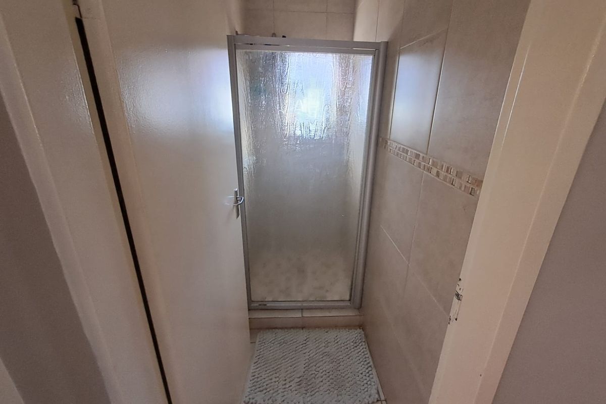 A compact bathroom featuring a shower enclosure with tiled walls and flooring.