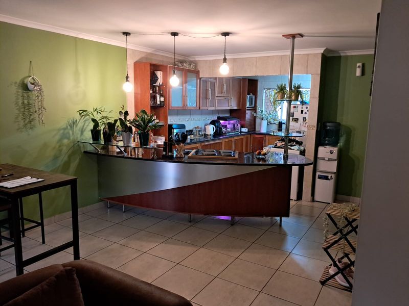Open plan kitchen featuring a breakfast bar with granite countertops, built-in cabinetry, and tiled flooring, seamlessly integrated into the living space.