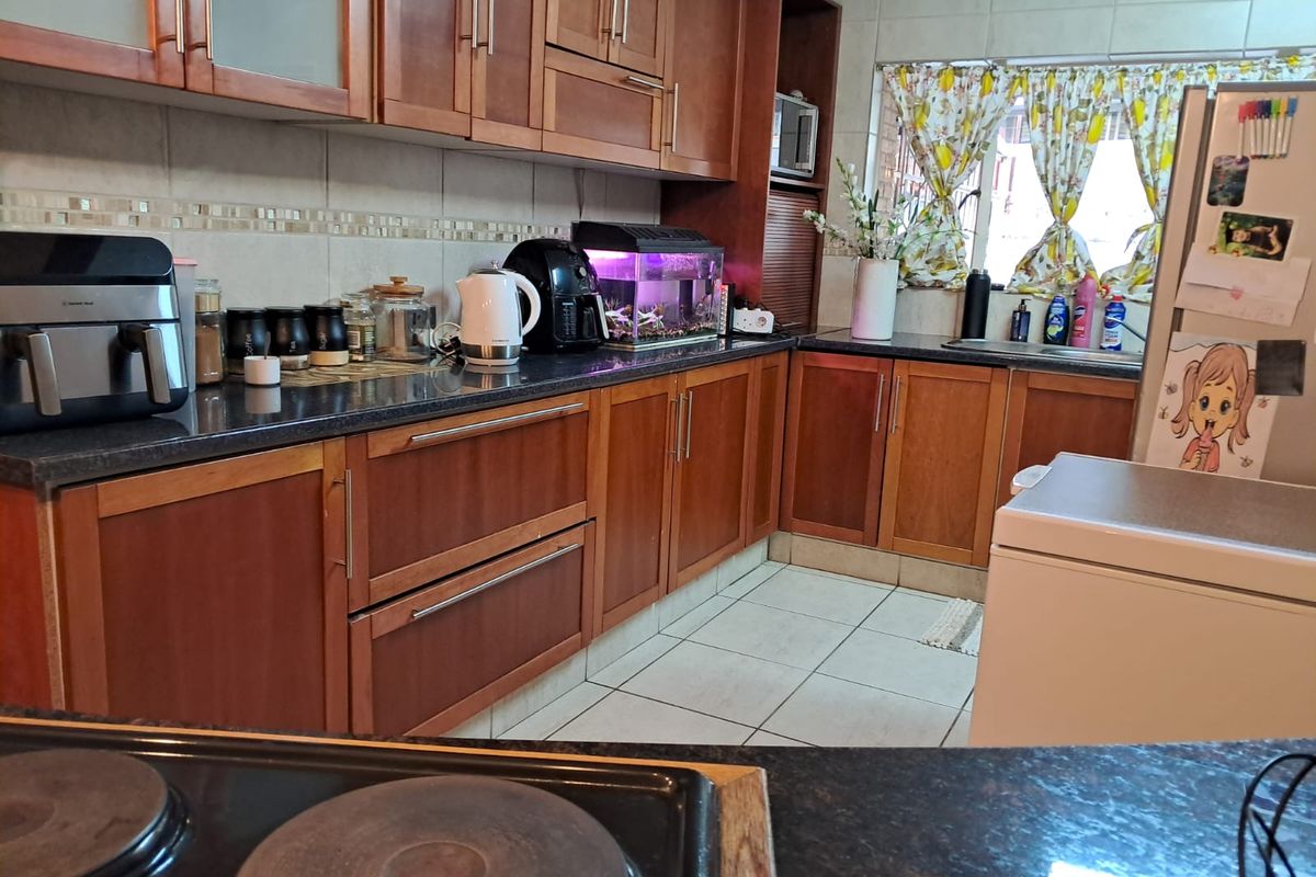 A functional kitchen featuring wooden cabinetry, granite countertops, tiled backsplash, and ceramic flooring, providing ample storage and workspace for daily meal preparation.