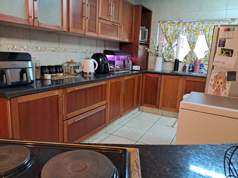 A functional kitchen featuring wooden cabinetry, granite countertops, tiled backsplash, and ceramic flooring, providing ample storage and workspace for daily meal preparation.