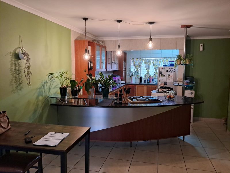 Open plan kitchen featuring a curved breakfast bar with granite countertop, built-in hob, and pendant lighting, seamlessly integrated into the living space.