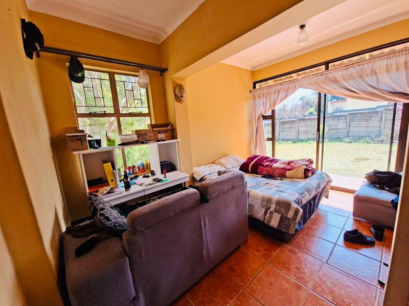 A bedroom featuring tiled flooring, large windows, and sliding glass doors that provide direct access to the outdoor area.