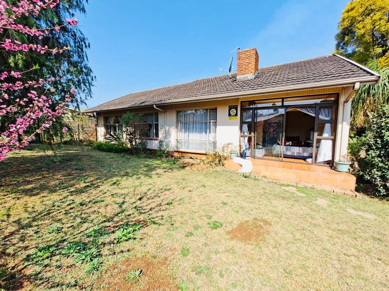 Rear view of the house featuring a tiled roof, brick chimney, and a paved patio area accessible through sliding glass doors.