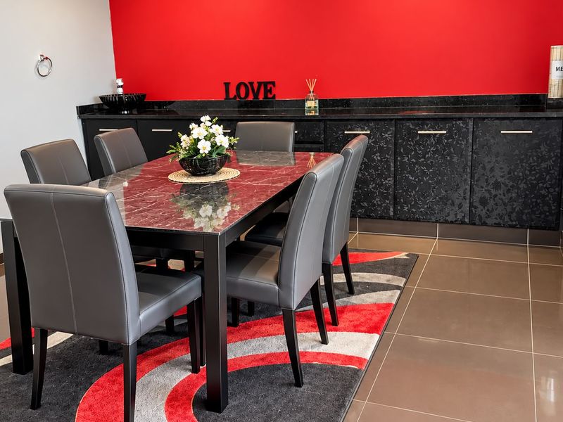 A formal dining area featuring dark built-in cabinetry with granite countertops, tiled flooring, and a bold red accent wall.