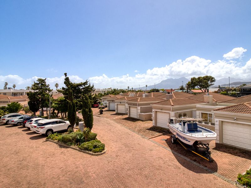 An elevated view of a residential complex featuring paved driveways, multiple garage units, and well-maintained exterior building finishes.