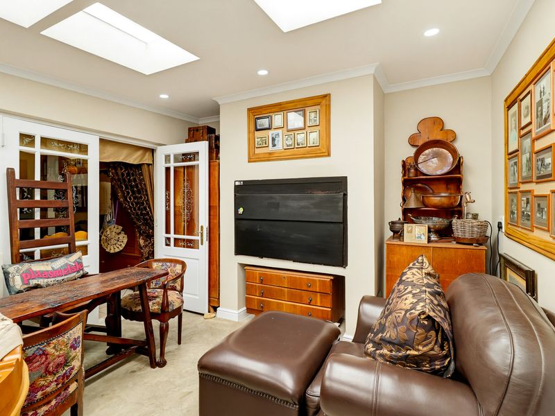A well-lit living area featuring dual skylights, recessed ceiling lighting, and classic French doors, providing a bright and inviting space.