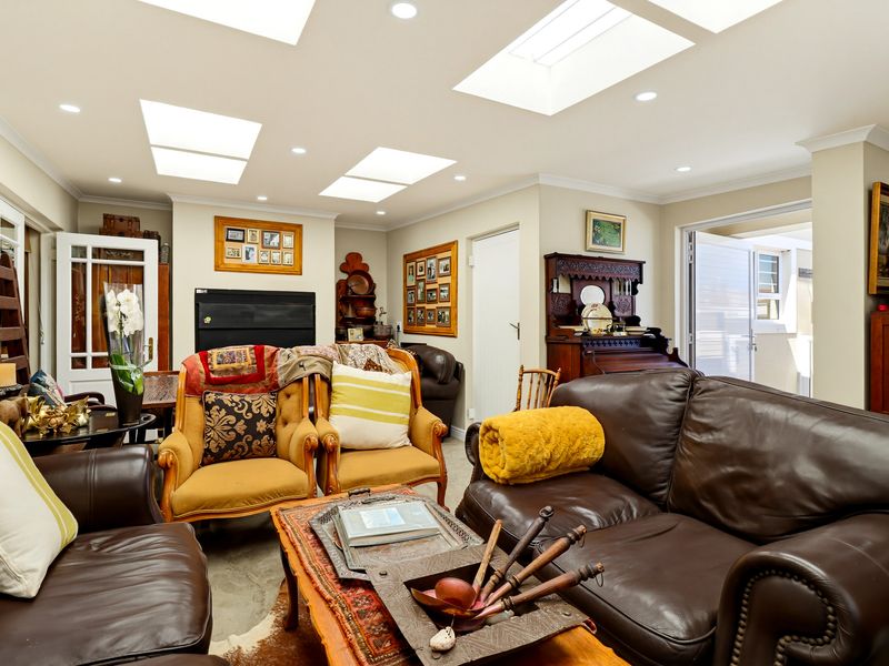 Spacious living room featuring multiple skylights, recessed lighting, and polished concrete floors, providing a bright and airy atmosphere with direct access to the patio.