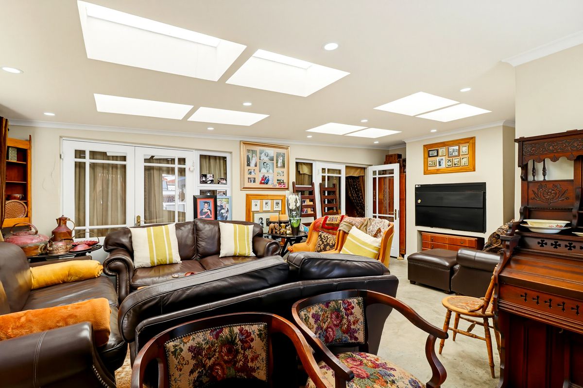 Spacious living room featuring multiple skylights, recessed lighting, and multiple sets of french doors providing ample natural light.